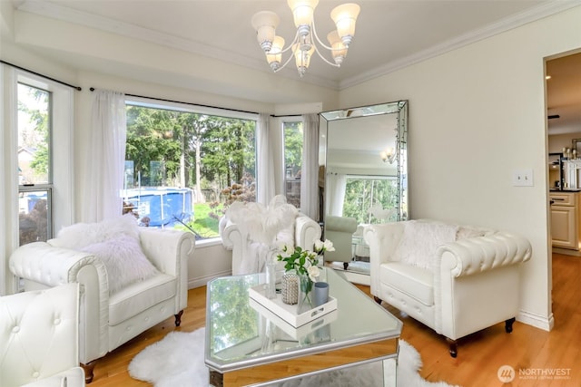 living area featuring a chandelier, ornamental molding, and light wood finished floors