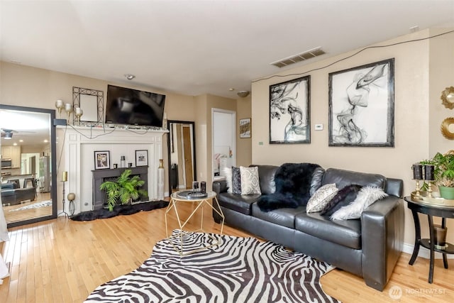 living room featuring visible vents, baseboards, and wood finished floors