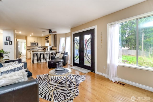 living room featuring light wood-style flooring, plenty of natural light, and french doors