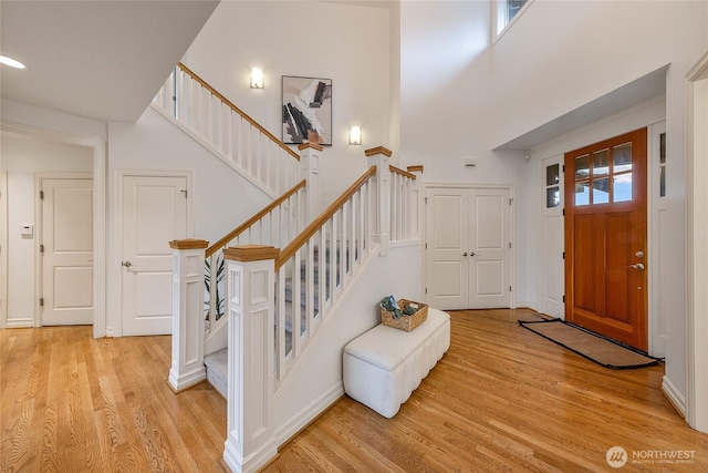 entryway featuring light wood finished floors, stairs, a high ceiling, and baseboards