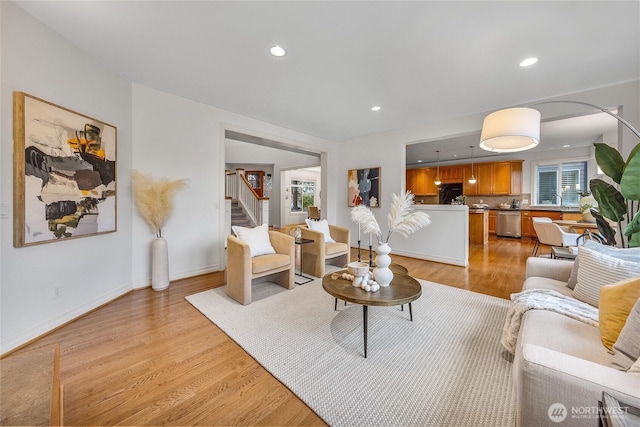 living room with a wealth of natural light, light wood-type flooring, and stairway