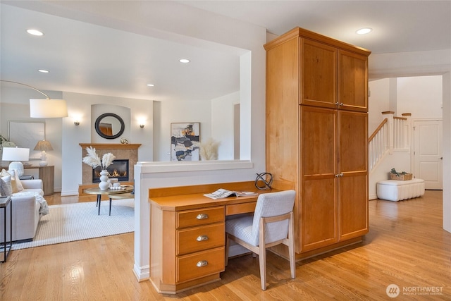 office with a glass covered fireplace, recessed lighting, and light wood-style floors