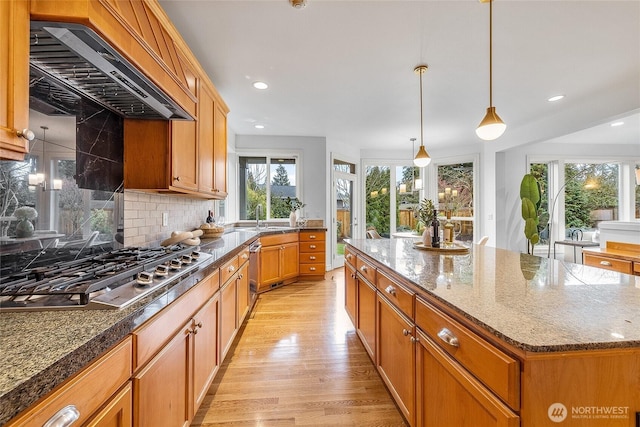 kitchen with light wood-style flooring, custom range hood, a sink, a center island, and stainless steel gas cooktop