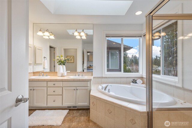 bathroom featuring double vanity, a garden tub, visible vents, and a sink