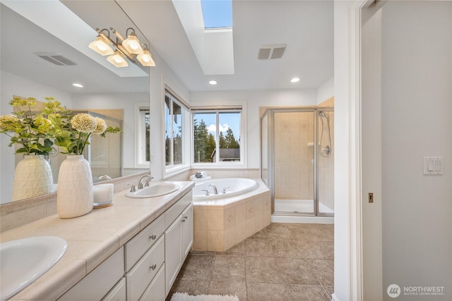 bathroom with visible vents, a garden tub, a sink, a skylight, and a shower stall