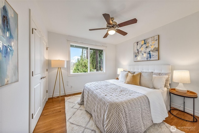 bedroom with baseboards, ceiling fan, and light wood finished floors