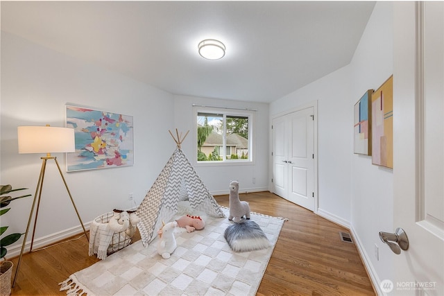 recreation room with wood finished floors, visible vents, and baseboards