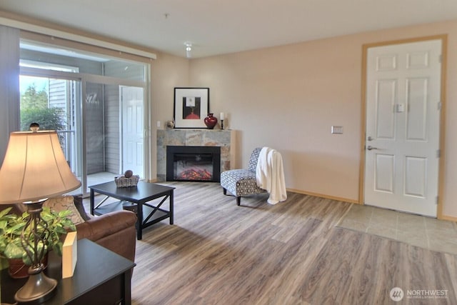 living room with a tiled fireplace, wood finished floors, and baseboards