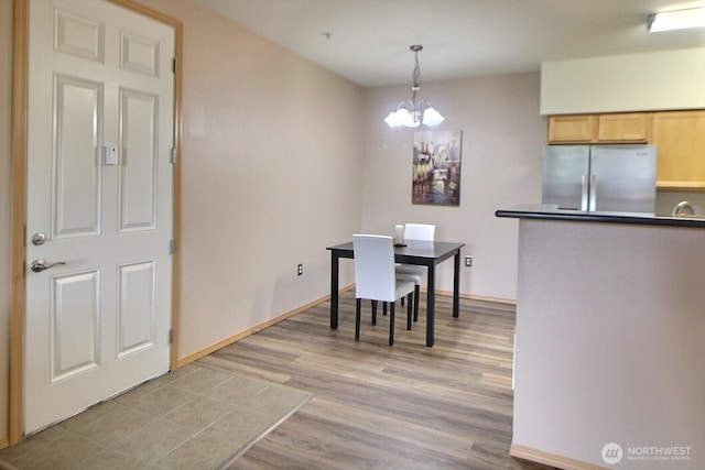 dining space with a notable chandelier, light wood-style floors, and baseboards