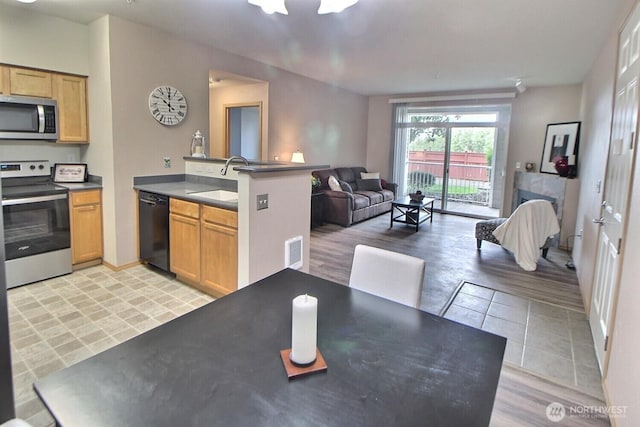 kitchen featuring visible vents, a sink, open floor plan, a peninsula, and appliances with stainless steel finishes