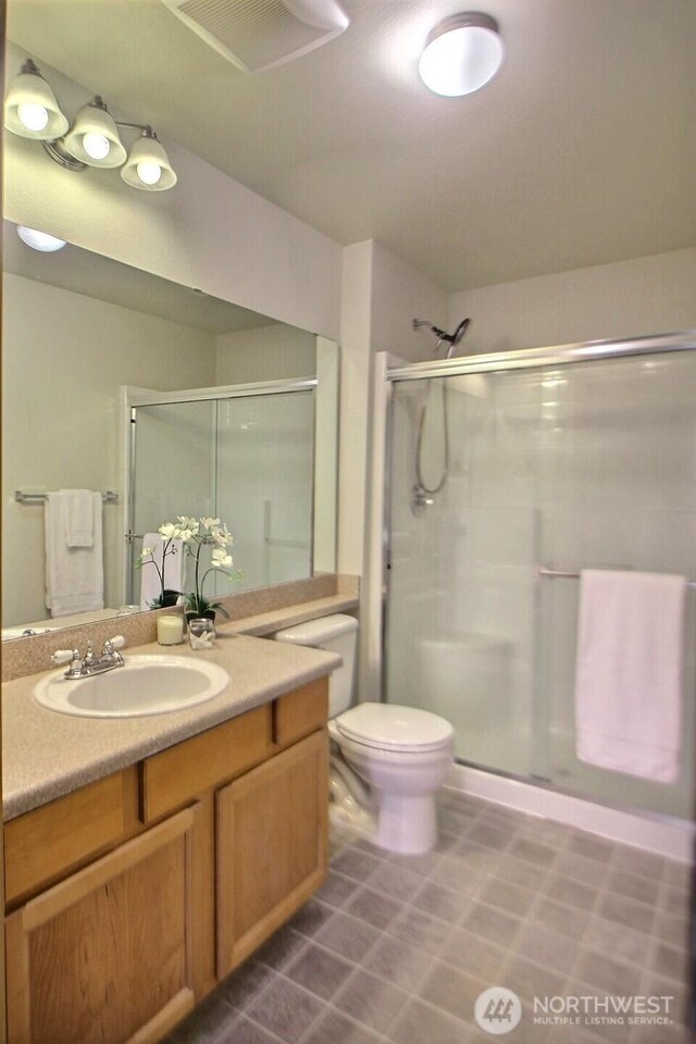 full bathroom featuring vanity, toilet, visible vents, and a stall shower