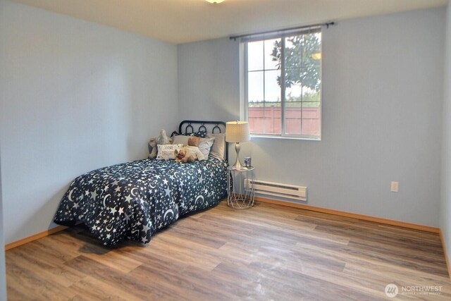 bedroom featuring baseboard heating, baseboards, and wood finished floors