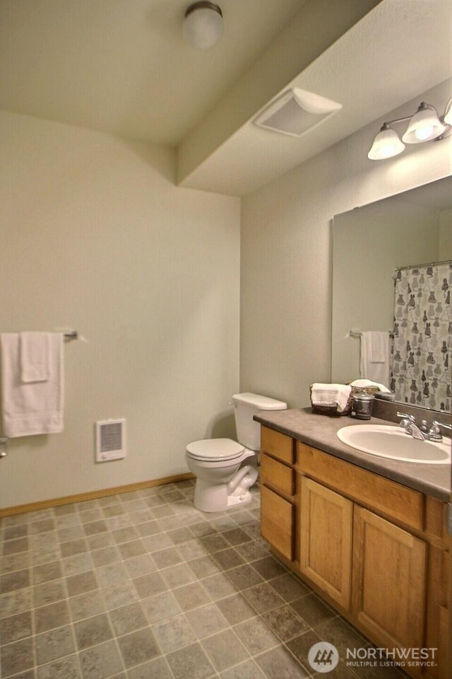 bathroom with curtained shower, toilet, vanity, and baseboards