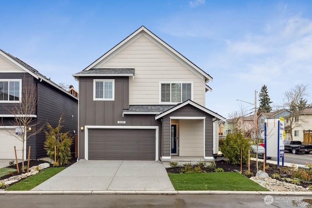 traditional home with board and batten siding, concrete driveway, a garage, and a shingled roof