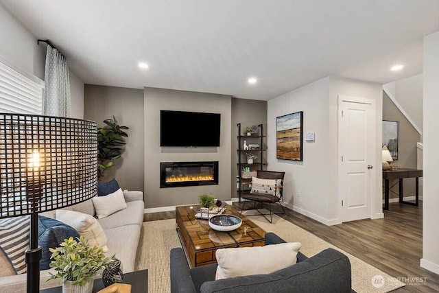 living area featuring a glass covered fireplace, recessed lighting, wood finished floors, and baseboards