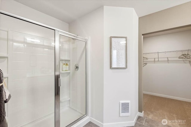 bathroom featuring a shower stall, a spacious closet, baseboards, and visible vents