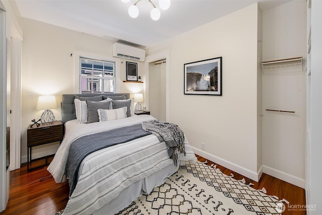 bedroom with an AC wall unit, light wood-style floors, and baseboards