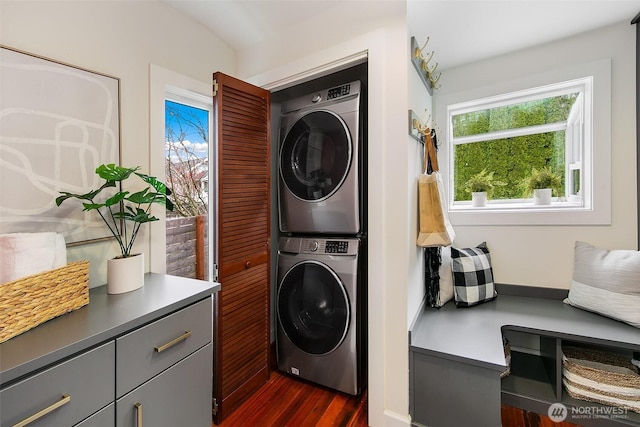 laundry area featuring laundry area, stacked washer / drying machine, and dark wood-type flooring