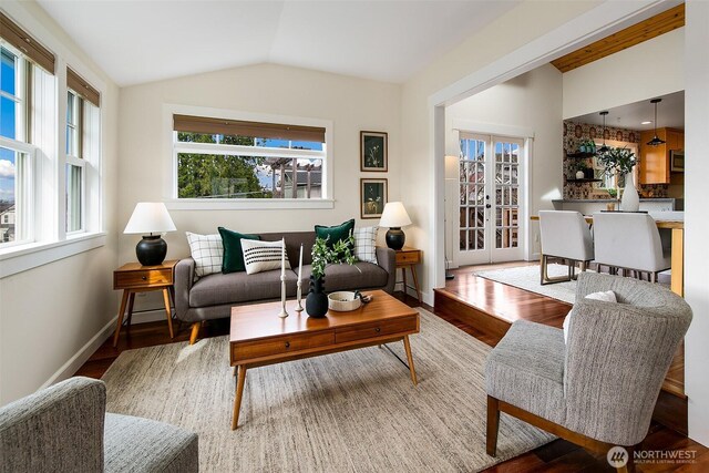 living area featuring french doors, wood finished floors, baseboards, and vaulted ceiling