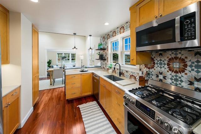 kitchen featuring a sink, dark wood finished floors, appliances with stainless steel finishes, light countertops, and decorative backsplash