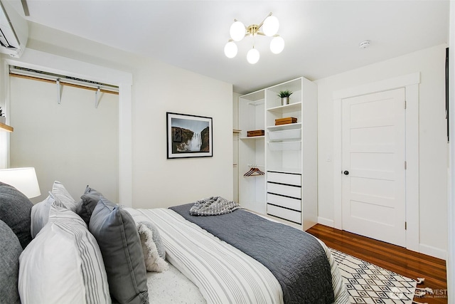 bedroom with dark wood finished floors and a wall mounted AC