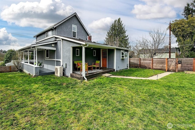 rear view of property featuring a yard, a fenced backyard, and stucco siding