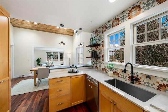 kitchen with a peninsula, a sink, light countertops, pendant lighting, and stainless steel dishwasher