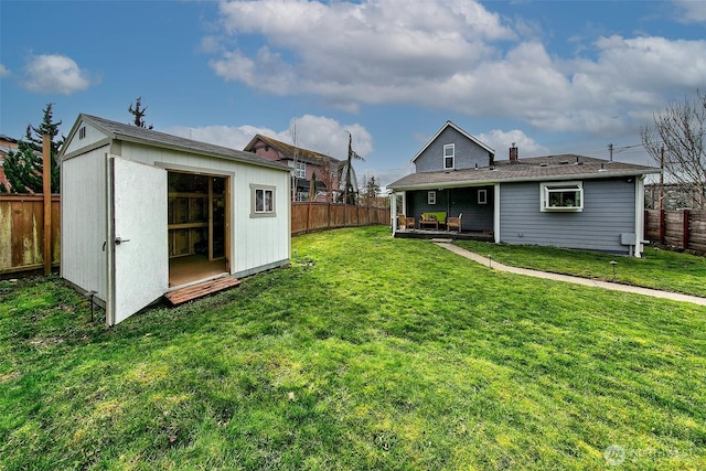 back of house featuring an outdoor structure, a yard, a fenced backyard, and a storage unit