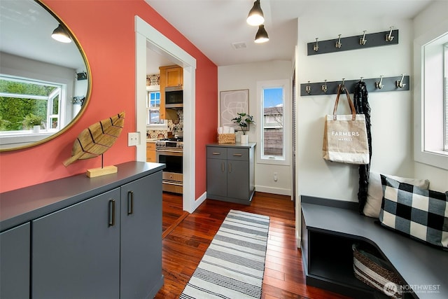 kitchen with dark countertops, visible vents, dark wood-type flooring, decorative backsplash, and stainless steel appliances