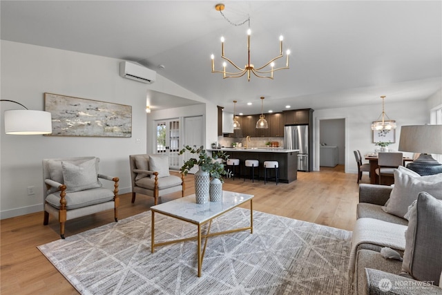 living area with a wall unit AC, vaulted ceiling, light wood-style floors, and a chandelier