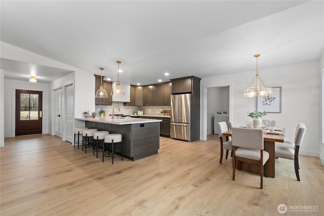 kitchen with a kitchen bar, washer / clothes dryer, a peninsula, light countertops, and high end refrigerator