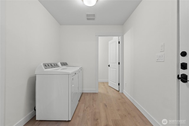 washroom with visible vents, light wood finished floors, baseboards, laundry area, and washing machine and clothes dryer