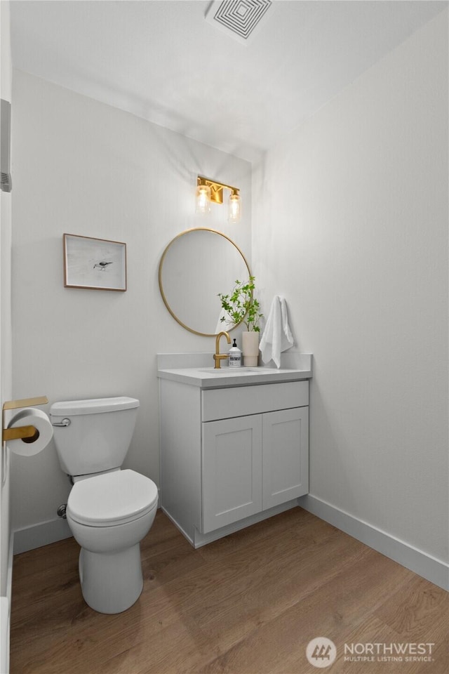 bathroom with visible vents, toilet, vanity, and wood finished floors