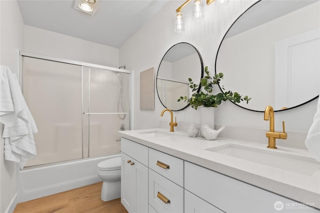 full bath featuring a sink, toilet, wood finished floors, and double vanity