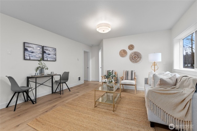 living area featuring visible vents, baseboards, and wood finished floors