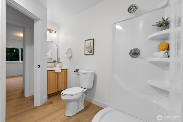 bathroom featuring toilet, wood finished floors, baseboards, walk in shower, and vanity