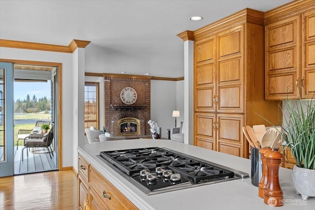 kitchen with light countertops, ornamental molding, a fireplace, and stainless steel gas cooktop