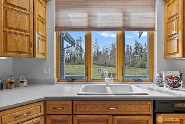 kitchen featuring light countertops, brown cabinetry, and a sink