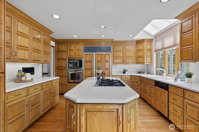 kitchen featuring a sink, built in appliances, a center island, and light wood finished floors