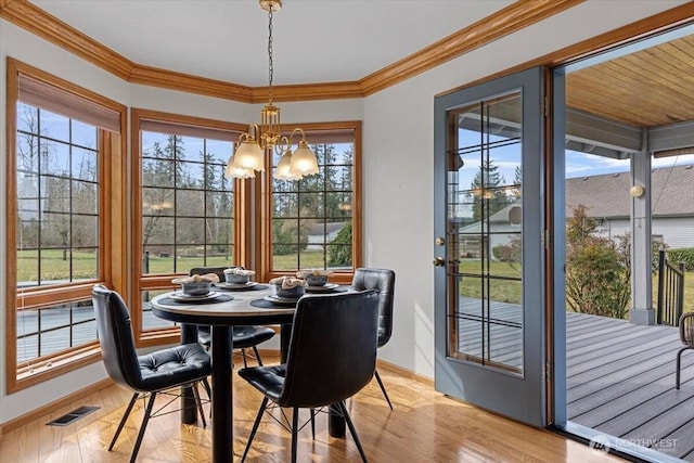 dining space featuring wood finished floors, baseboards, visible vents, an inviting chandelier, and ornamental molding