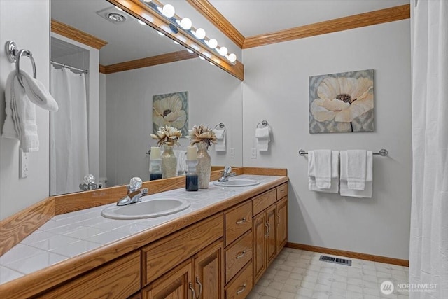 bathroom featuring a sink, baseboards, crown molding, and tile patterned floors