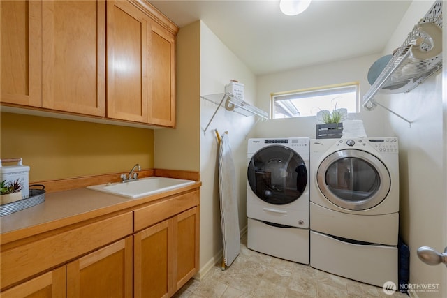 laundry room with washer and dryer, cabinet space, and a sink