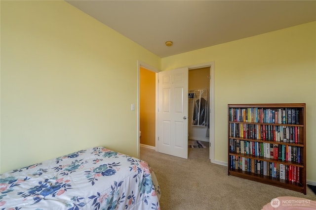 carpeted bedroom featuring a walk in closet and baseboards