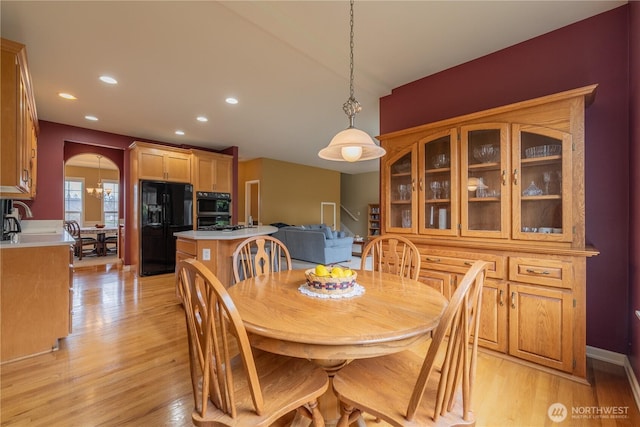 dining room with arched walkways, recessed lighting, light wood finished floors, and stairs