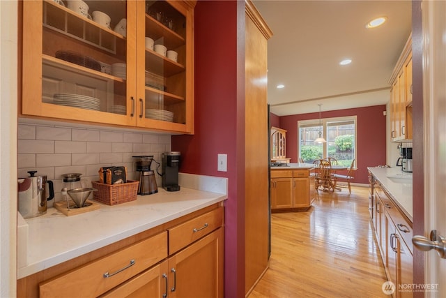 kitchen featuring baseboards, light wood-style flooring, recessed lighting, decorative backsplash, and decorative light fixtures