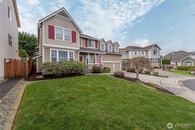 view of front of house featuring an attached garage, fence, a residential view, a front yard, and driveway