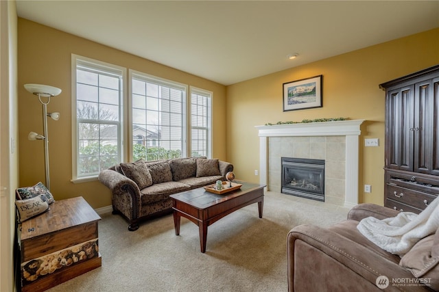 living area with baseboards, carpet, and a tiled fireplace