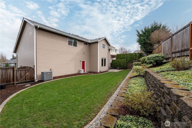 rear view of property featuring a yard, a fenced backyard, central AC, and a gate