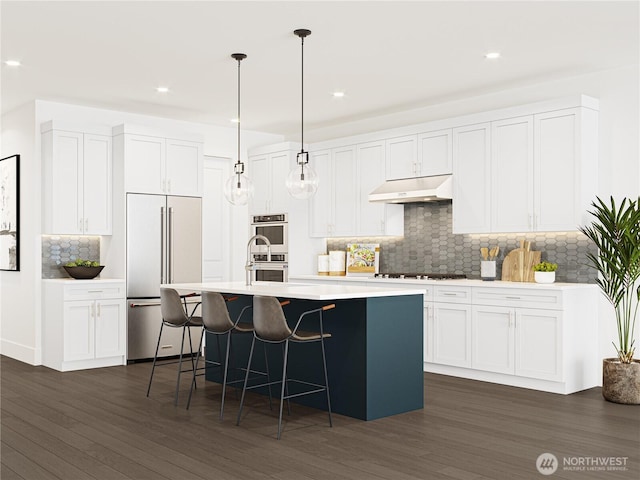 kitchen with under cabinet range hood, dark wood finished floors, decorative light fixtures, an island with sink, and high end refrigerator