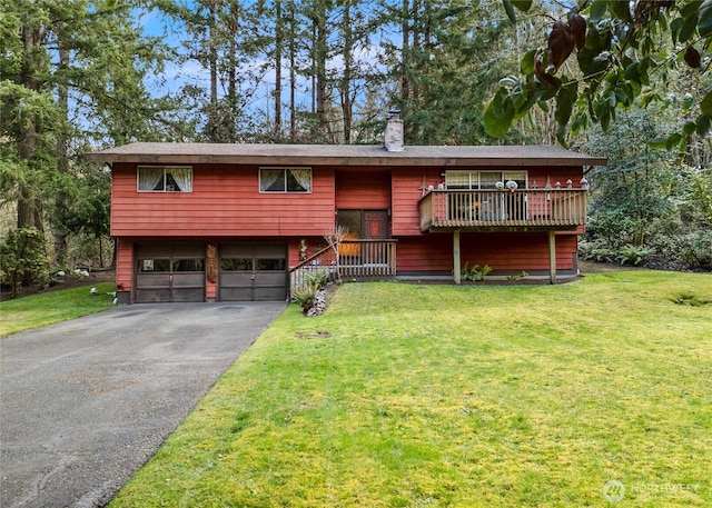 split foyer home with a chimney, driveway, a front lawn, and a garage